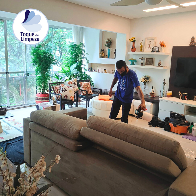 Imagem de funcionário em serviço, limpando e higienizando sofá.